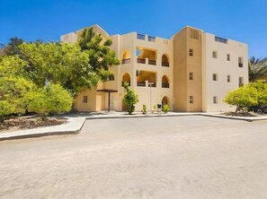 A multi-story building with a central courtyard, balconies, and greenery. - El Gouna luxury apartment lagoon and pool view (Red Sea Governorate)