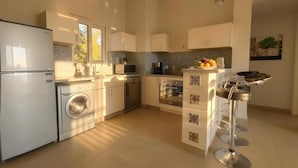 A modern kitchen with a washing machine, oven, and a bar stool. - El Gouna luxury apartment lagoon and pool view (Red Sea Governorate)
