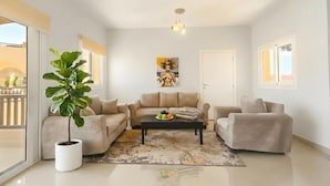 A modern living room with a beige sofa set, a coffee table, a potted plant, and a painting on the wall. - El Gouna luxury apartment lagoon and pool view (Red Sea Governorate)