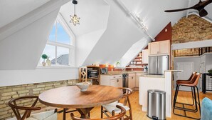 A modern loft apartment with a dining area, kitchen, and a large window. - Cuckoo's Nest 3BR Traverse City condo (Traverse City)