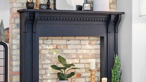 A brick fireplace with a mirror above it, a small wooden table with candles, and a potted plant. - Cuckoo's Nest 3BR Traverse City condo (Traverse City)