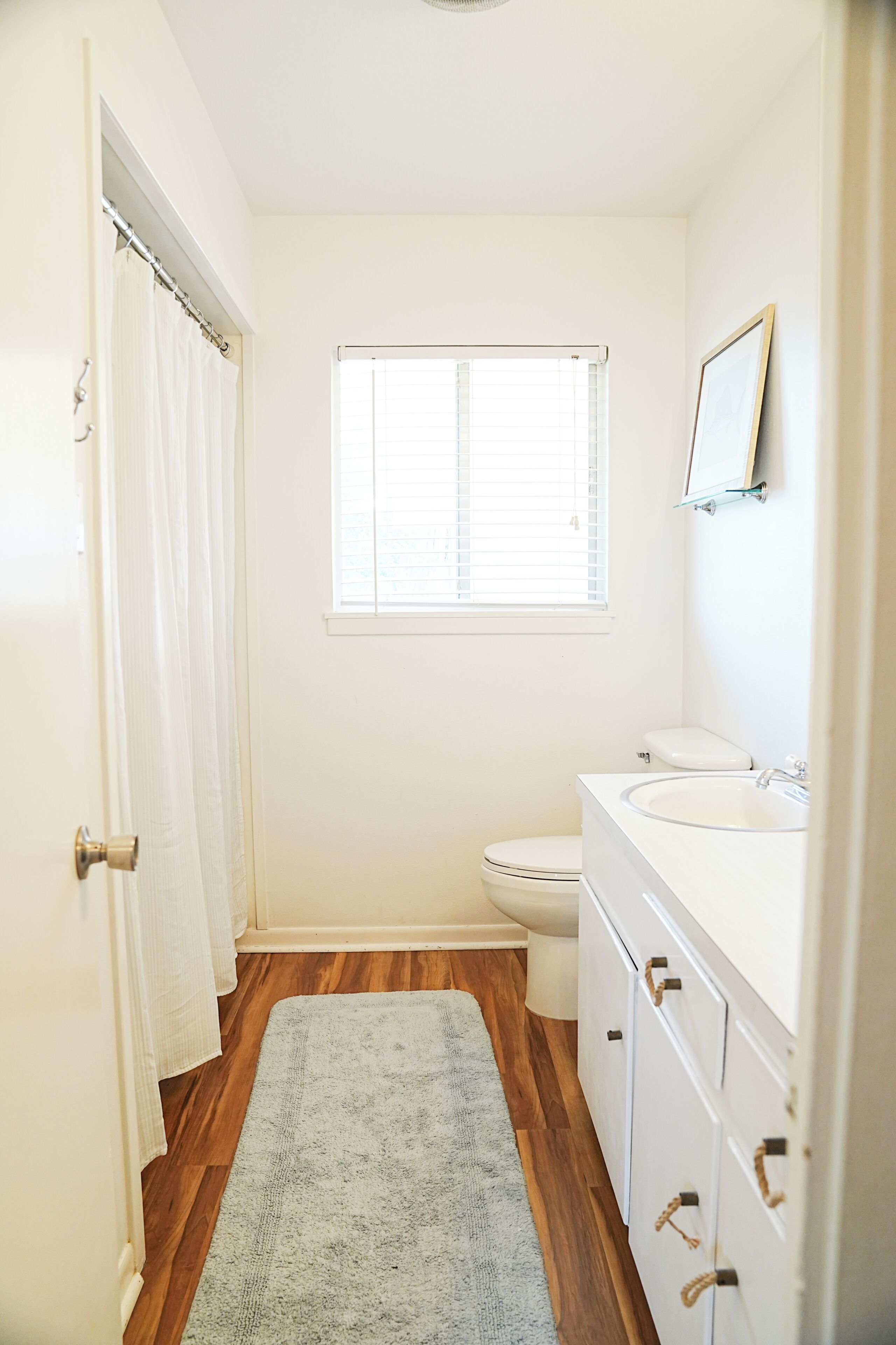 A bathroom with a toilet, sink, and window.