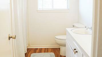 A bathroom with a toilet, sink, and window.