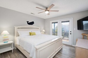A bedroom with a bed, a ceiling fan, a TV, and a balcony. - 418 - Nags Head Sound-side retreat with hot tub! (Nags Head)