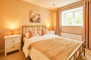 Ein Schlafzimmer mit Bett, Nachttischen, einem Fenster mit Vorhängen und einem Wandbild.