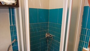 A shower with a glass door, blue-tiled walls, and a white shower control panel.