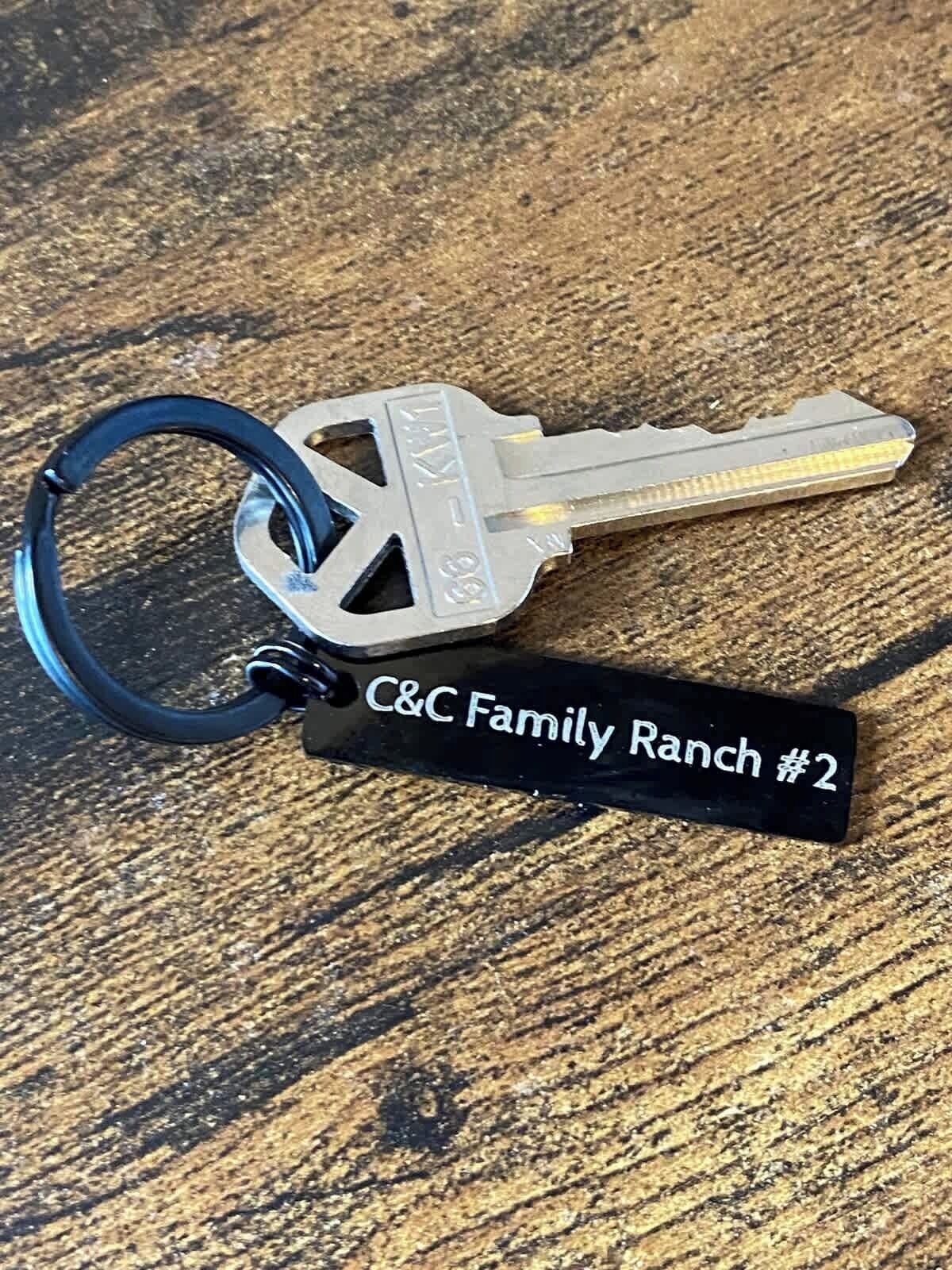 Un juego de llaves con un llavero que dice "C&C Family Ranch #2" sobre una superficie de madera.