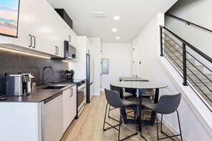 A modern kitchen with a built-in oven, a coffee machine, and a dining area with a round table and two chairs. - Stay in Pure Luxury With Resort-style Amenities! (New Braunfels)