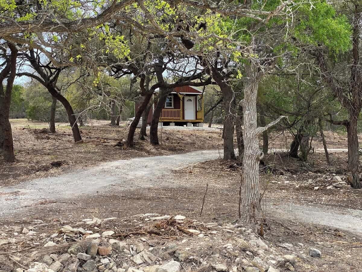 Eine rustikale Holzhütte, umgeben von Bäumen, mit einem Feldweg, der zur Hütte führt.
