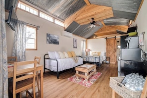 A cozy room with a bed, a wooden chair, a small table, and a refrigerator. - Hill Country Cabin 3 (Canyon Lake)