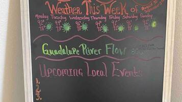 A chalkboard with a welcome message, weekly weather forecast, and upcoming local events.