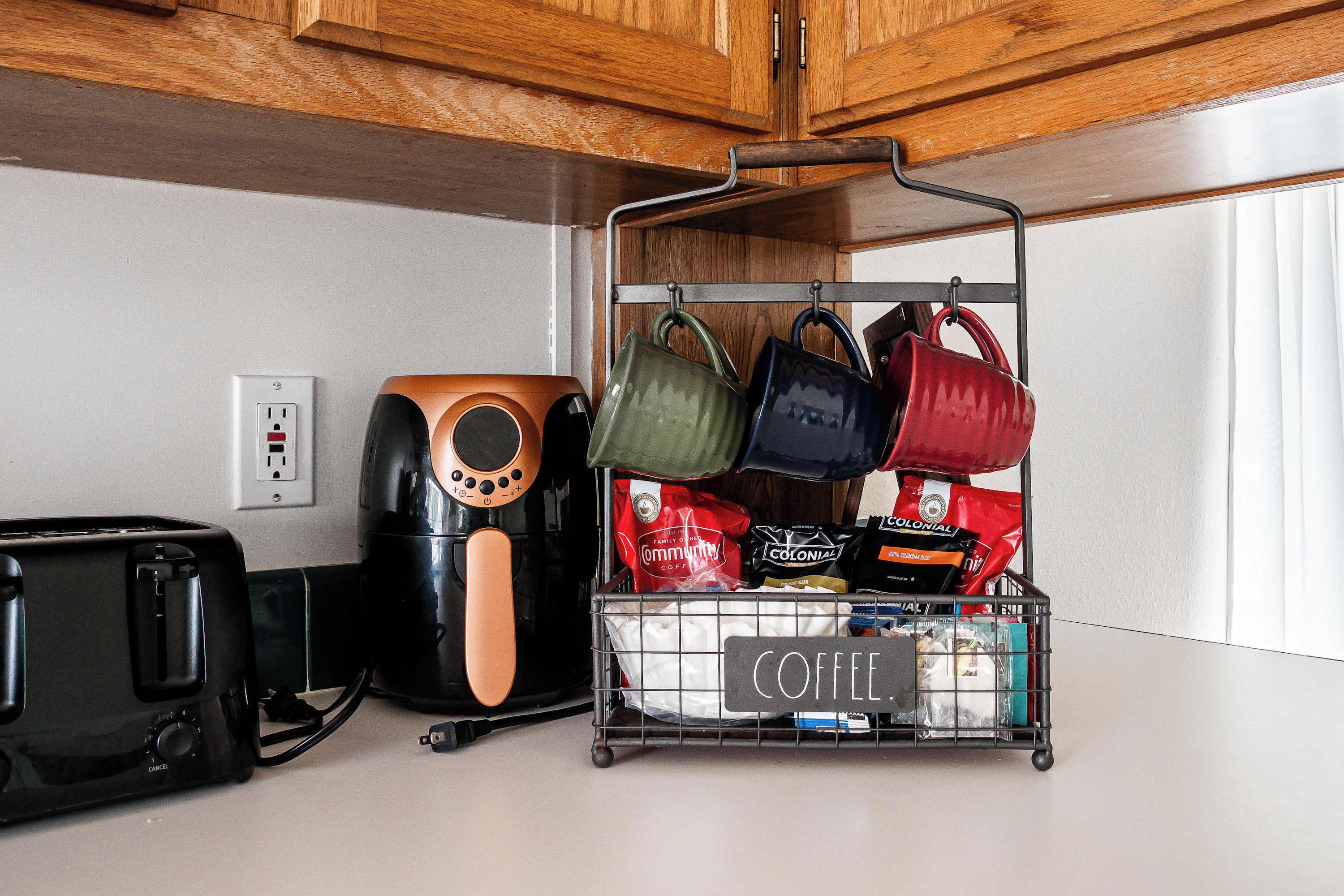 A kitchen with a coffee station, a toaster, a coffee maker, and a hanging rack with bags.