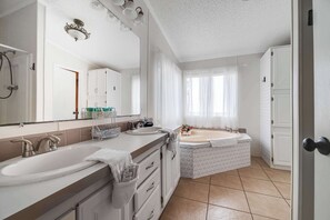 Une salle de bain avec deux lavabos, une baignoire et un grand miroir.