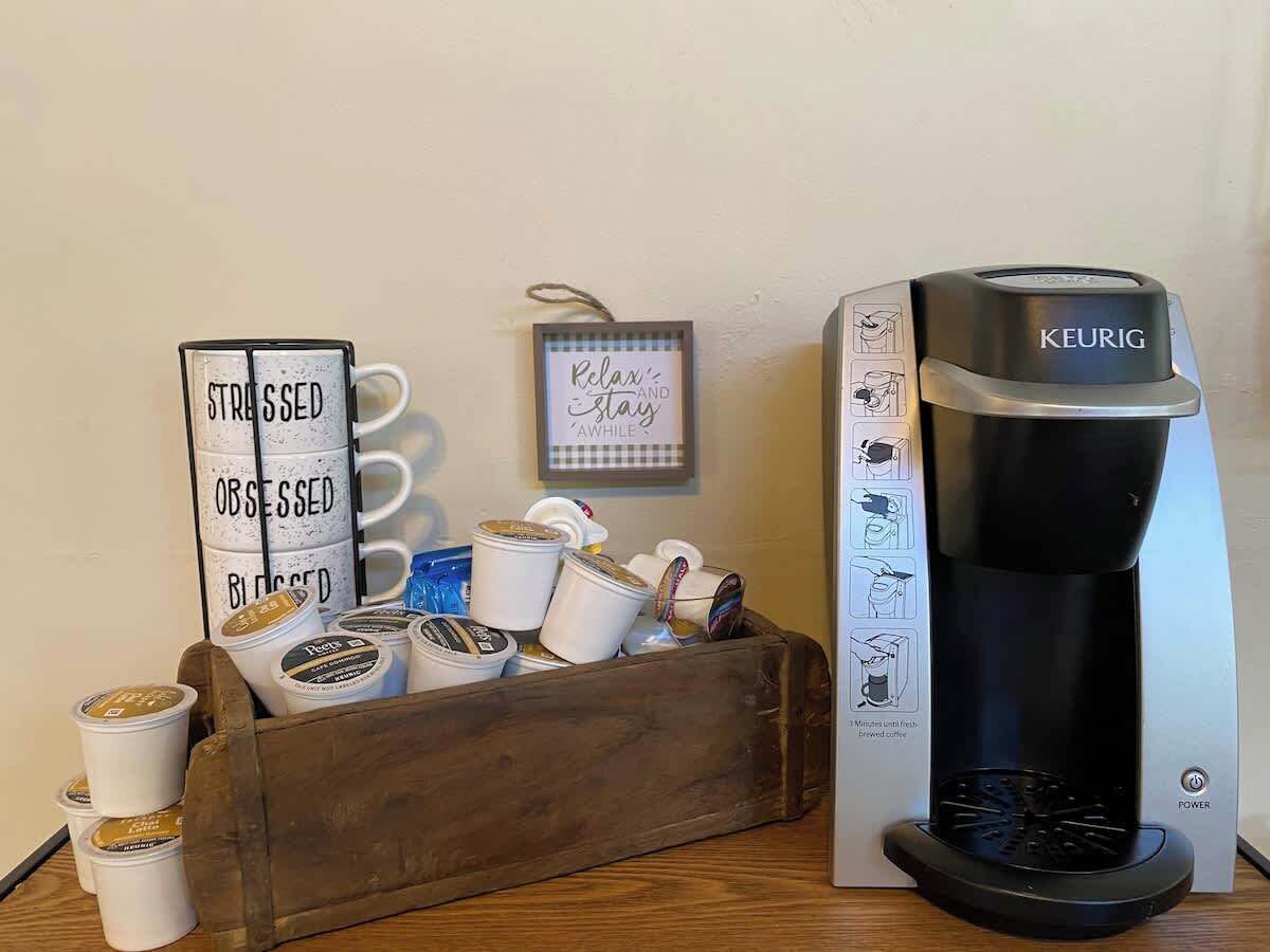 Een koffiezetapparaat, een houten kist met koffiekopjes en verpakkingen, en een motiverende tekstbord.