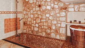 A bathroom with a stone wall, a tiled floor, a shower, and a sink with a wicker basket. - SA TANQUETA DE CALONGE (Santanyí)