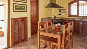 A kitchen with wooden cabinets, a stove, and a dining table with chairs. - SA TANQUETA DE CALONGE (Santanyí)