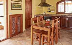 Une cuisine avec des meubles de rangement en bois, une cuisinière et une table à manger avec des chaises.