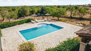 A swimming pool with stone tiles, surrounded by lounge chairs and umbrellas, set against a rural backdrop. - SA TANQUETA DE CALONGE (Santanyí)