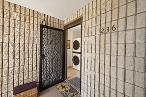 Ein Flur mit Wandverkleidung, einer Tür mit Gitterelementen, einer Bank und der Zahl '236' an der Wand.