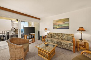 A living room with a television, a sofa, a coffee table, and two lamps. - 🌴 Alii Villas #236 | Ocean Views | Pool | Centrally Located | New Listing (Kailua Kona)