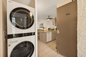 A laundry room with two stacked washers and dryers, a kitchen area with a countertop and a ceiling fan, and a door labeled '236'. - 🌴 Alii Villas #236 | Ocean Views | Pool | Centrally Located | New Listing (Kailua Kona)