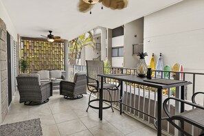 Un balcon agrémenté de meubles en osier, d’une table et d’un ventilateur de plafond.