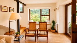 A room with two wicker chairs, a floor lamp, a sofa, a window with a view of greenery, and a potted plant. - House with a Garden · Ribadesella · La Cuadra San Pedro (Ribadesella)