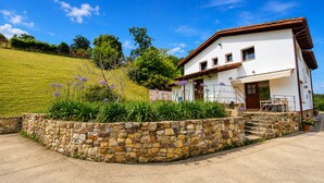 A two-story house with a stone wall and a wooden staircase leading to the entrance. - House with a Garden · Ribadesella · La Cuadra San Pedro (Ribadesella)