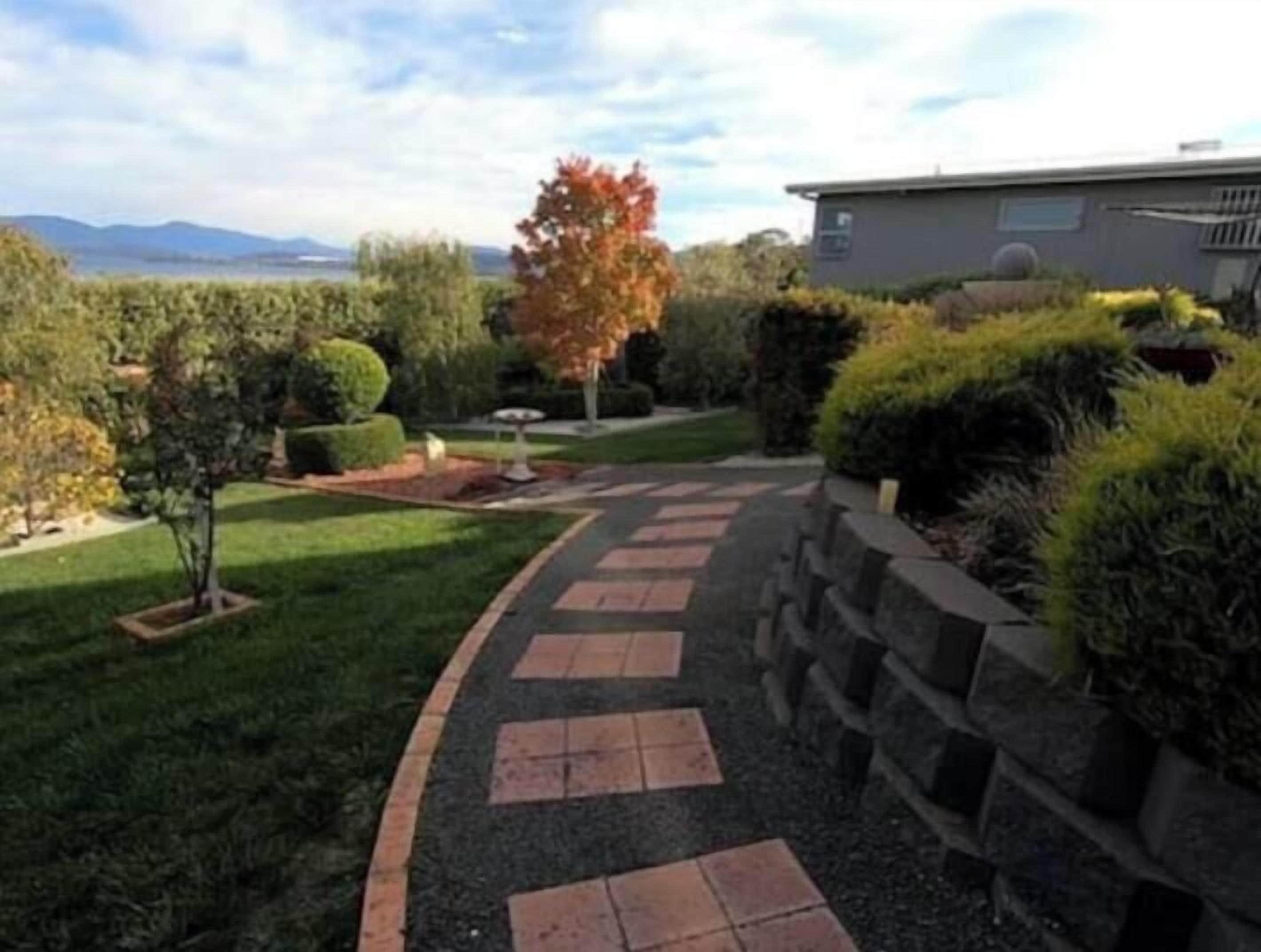A landscaped pathway leading to a building with a view of the mountains.