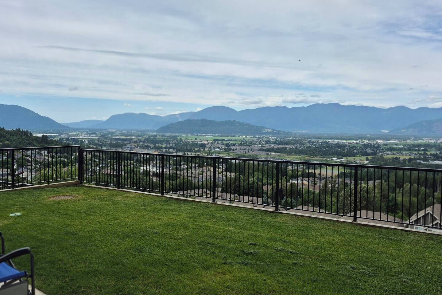 A balcony with a metal railing overlooking a cityscape with mountains in the distance.
