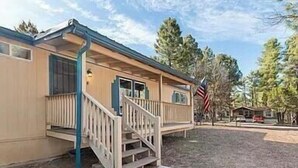 A single-story building with a front porch, a flag, and a clear sky. - Remodeled Cabin in the Heart of Lakeside (Lakeside)