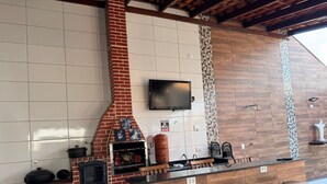 Una cocina con horno de ladrillo, televisor de pantalla plana y barra con taburetes.