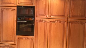 Una cocina con armarios de madera y electrodomésticos integrados, incluyendo un microondas y un horno.