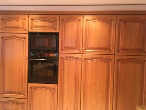 A kitchen with wooden cabinetry and built-in appliances including a microwave and oven. - Haus Falke Appartement/Fewo 6-Bettwohnung by Interhome (Saas-Balen)
