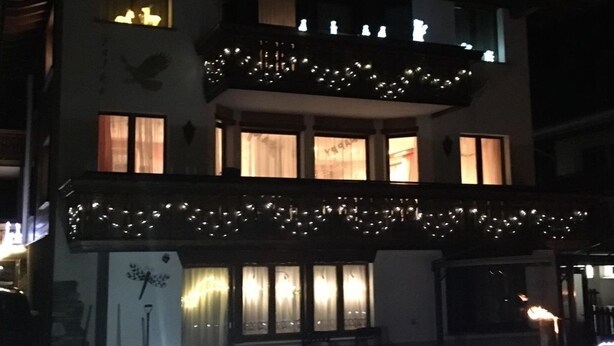 Un edificio de dos pisos con un balcón, luces colgantes y un suelo cubierto de nieve.