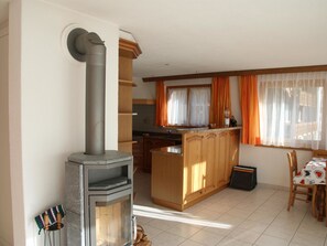 Une cuisine équipée d’un poêle à bois encastré, de meubles de rangement en bois et d’un coin repas avec une table et des chaises.