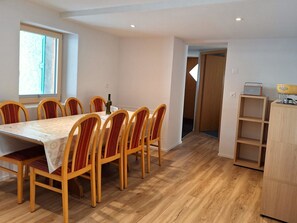 Ein Essbereich mit Tisch und Stühlen, einem Fenster, einer Tür und einem Holzschrank.