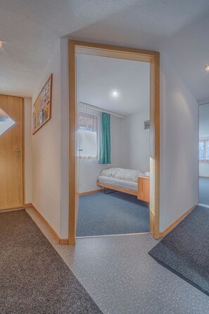 Ein Zimmer mit Bett, Tür und einem Vorhangfenster.