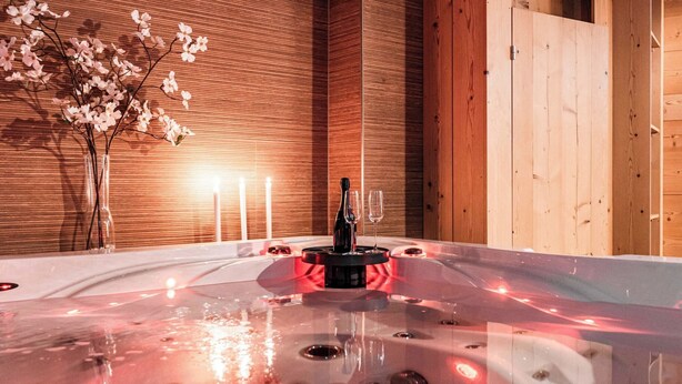 A hot tub with a wooden wall and a vase of flowers. - Kusi's Ranch Appartement/Fewo Dachwohnung by Interhome (Saas-Fee)