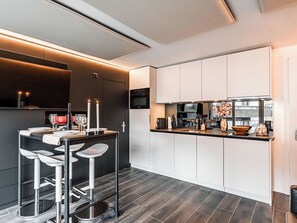 A modern kitchen with a central island, bar stools, and a built-in oven. - Kusi's Ranch Studio Studio Nr. 11 Täschhorn by Interhome (Saas-Fee)
