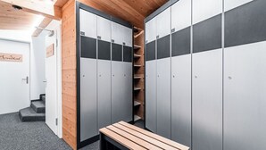 Un vestiaire avec des casiers gris, un banc en bois et un mur en bois.