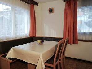A dining area with a table, chairs, and a bowl of fruit. - Floralpina Appartement/Fewo Wohnung Nr. 507 by Interhome (Saas-Fee)