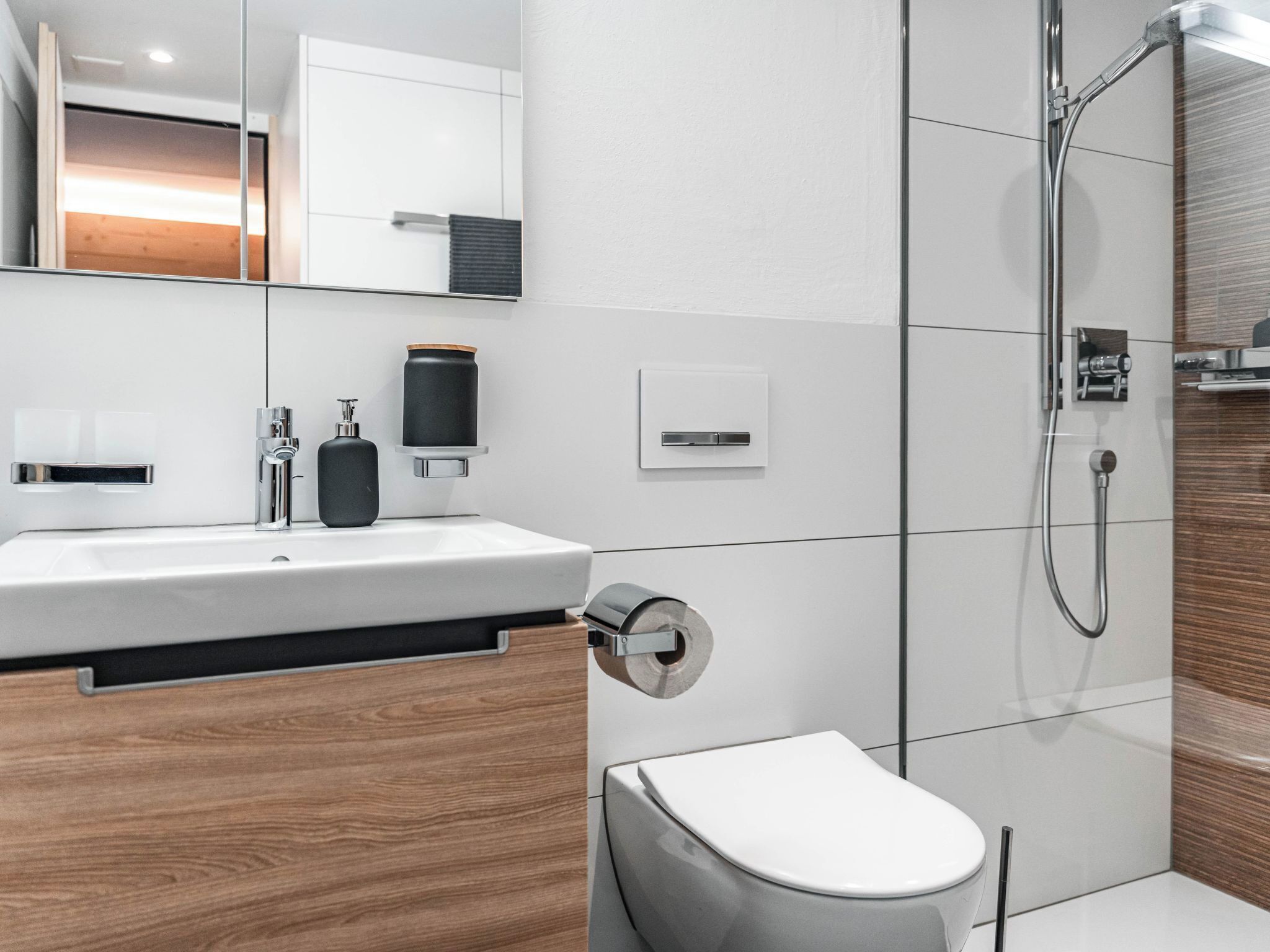 Une salle de bain moderne avec un lavabo blanc, un meuble-lavabo en bois, des toilettes et un espace douche.