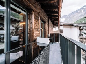 A wooden exterior with large windows, a balcony, and a mountain view. - Kusi's Ranch Studio Studio Nr. 12 Nadelhorn by Interhome (Saas-Fee)