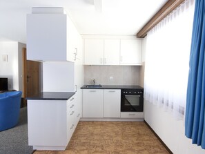 Eine kompakte Küche mit weißen Schränken, einer schwarzen Arbeitsplatte und einem eingebauten Backofen.