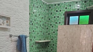 Ein Badezimmer mit gefliestem Boden, Toilette, Waschbecken und Duschbereich.