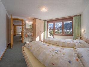Ein Schlafzimmer mit zwei Betten, einem Badezimmer und Blick auf Berge.