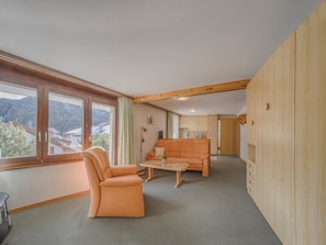 Ein Wohnzimmer mit einer Couch, einem Sessel, einem Couchtisch und Blick durch große Fenster.