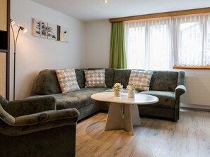 A living room with a sectional sofa, a round coffee table, and a floor lamp. - Abendstern Appartement/Fewo 5-Bettwohnung by Interhome (Saas-Almagell)
