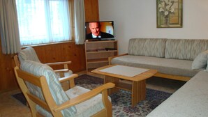Una sala de estar con un sofá, una silla, un televisor y un cuadro en la pared.